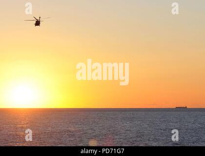 Einem MH-60R Seahawk Helikopter Hubschrauber Maritime Strike Squadron (HSM) 70 zugewiesen, und der Flugzeugträger USS George H.W. Bush (CVN 77) fliegt über den Atlantik bei Sonnenaufgang 17. Okt. 2010. George H.W. Bush ist die Durchführung von massgeschneiderten Trainings des Schiffes Verfügbarkeit/abschließende Bewertung problem. (U.S. Marine Foto von Mass Communication Specialist 3. Klasse Tony Curtis/Freigegeben) Stockfoto