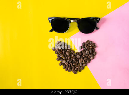 Ansicht von oben flache Schicht Funny Face von Kaffeebohnen in lächeln Symbol Form hergestellt, und Sonnenbrille auf zwei Ton bunten Hintergrund Stockfoto