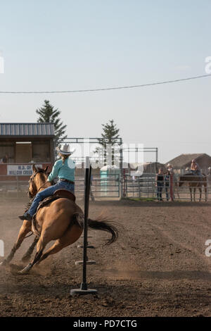 Ein junges Mädchen auf dem Pferderücken konkurriert in der Pole Bending Konkurrenz an der Nanton Nite Rodeo, Nanton, Alberta, Kanada Stockfoto