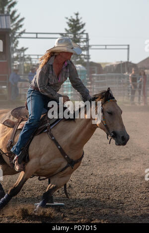 Ein junges Mädchen auf dem Pferderücken konkurriert in der Pole Bending Konkurrenz an der Nanton Nite Rodeo, Nanton, Alberta, Kanada Stockfoto