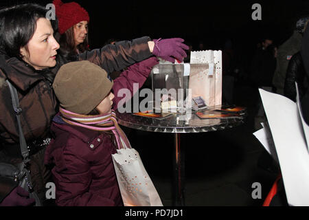 Kleine Mädchen und andere Leute Geld Spenden für wohltätige Zwecke und für die öffentliche Nutzung in Sofia, Bulgarien Hilfe - Dec 02, 2011. Spenden Konzept. Stockfoto