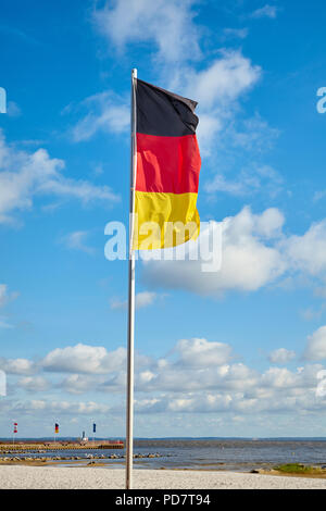 Deutsche Flagge auf einer Stange gegen den Himmel an einem sonnigen Tag. Stockfoto