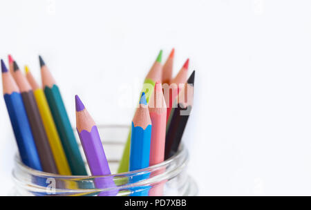 Bunte wachsmalkreiden im Glas. Vordere Stifte im Fokus. Weißer Hintergrund. Stock Bild. Stockfoto