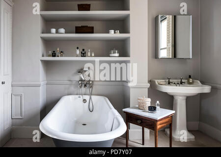 Frei stehende Roll Top Bad von Albion im Badezimmer mit antiken Marmortisch gekrönt und eingebaute Regale. Die Außenseite des Bades ist im Raili gemalt. Stockfoto