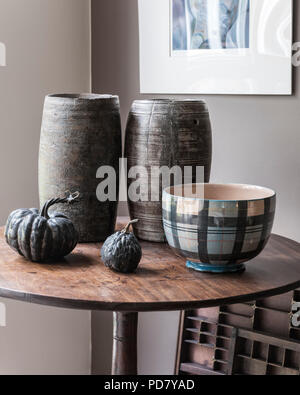 Zwei Holz- Töpfe aus Südafrika sind auf einem kleinen Tisch im Wohnzimmer mit getrockneten Kürbisse und eine Schale aus Anta angezeigt. Stockfoto