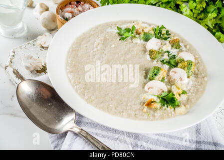 Mushroom champignon Cremesuppe in eine Schüssel geben und mit Petersilie, weissem Marmor Background Copy space Stockfoto