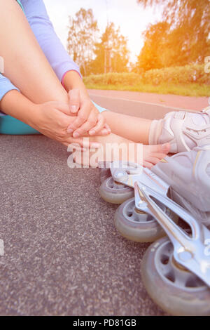 Verletzte skater sitzen und ihren schmerzlichen Bein Holding Stockfoto