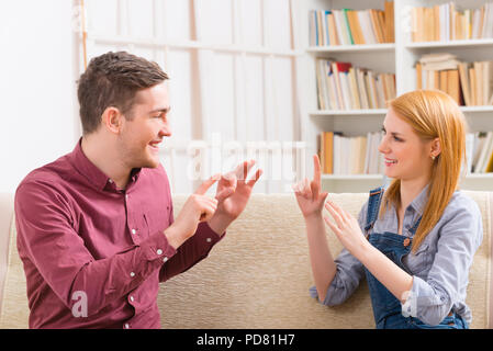 Lächelnden jungen Frau sprechen mit Gebärdensprache mit ihrer Hörbehinderung Mann Stockfoto