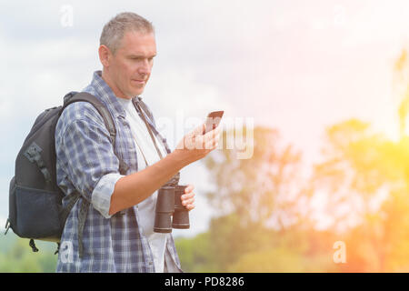 Mann Backpacker mit Smart Phone und Holding Fernglas Stockfoto