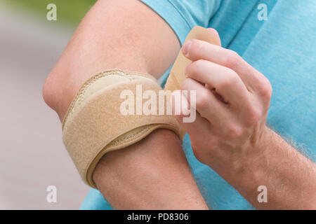 Mann, der Ellenbogen Bandage Schmerz zu verringern Stockfoto