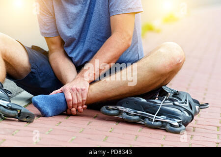 Verletzte skater sitzen und seine schmerzhaften Bein Holding Stockfoto