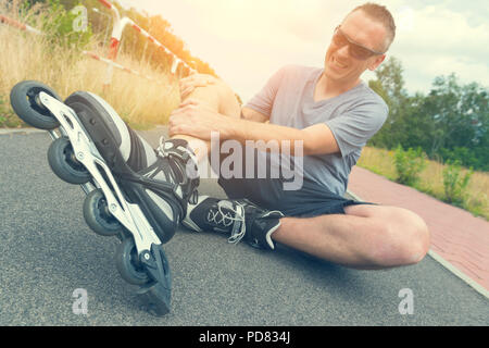 Verletzte skater sitzen und seine schmerzhaften Bein Holding Stockfoto