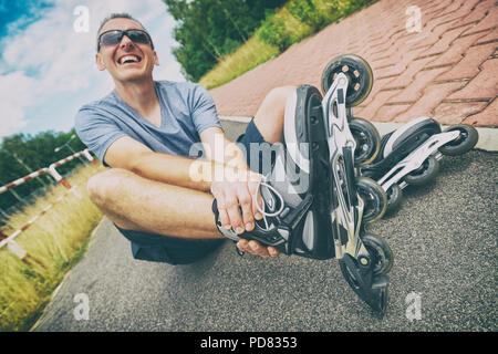 Verletzte skater sitzen und seine schmerzhaften Bein Holding Stockfoto