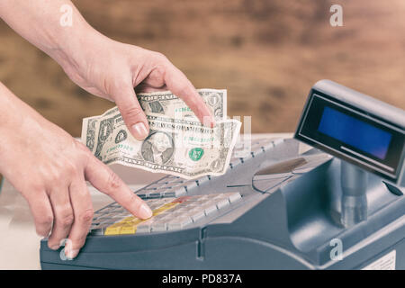 Kassierer holdnig Banknoten und über Kasse in Shop Stockfoto