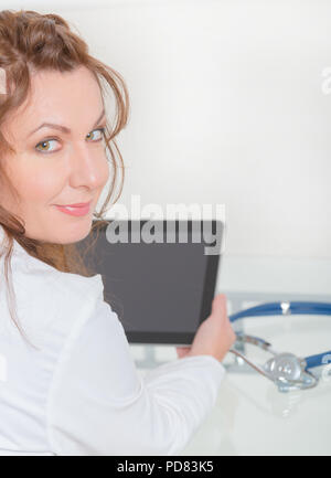 Frau Arzt mit Tablet-PC im Sprechzimmer Stockfoto