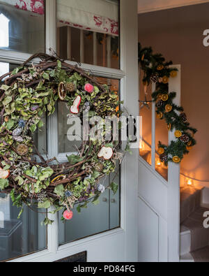 Weihnachten Kranz auf Öffnen der vorderen Tür durch festliche Eingangshalle, die Stockfoto