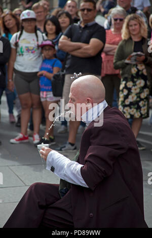 Edinburgh, Schottland, Großbritannien, 7. August 2018, Edinburgh Fringe auf der Royal Mile, an einem sonnigen Nachmittag die erhabenen zum auf der Straße mit einem blinkenden street Statue und ein strassenkünstler Roman weise Gebrauch von Sanitär Kolben und einige interessante Suchen sie das Publikum zu machen. Anthony Wohnfläche. Stockfoto