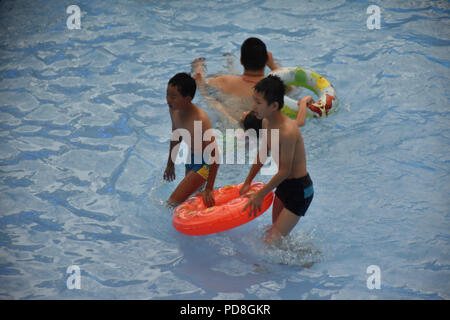 Peking, Peking, China. 8 Aug, 2018. Peking, China - Menschen genießen Sie die kühle am Wasser Park von Beijing National Aquatics Centre in Peking, China. Die Pekinger National Aquatics Center, auch als das Wasser Cube genannt, ist ein schwimmzentrum, die neben Peking Nationalstadion in der Olympischen Grün für die Schwimmwettbewerbe der Olympischen Sommerspiele 2008 errichtet wurde. Trotz seiner Spitznamen, das Gebäude ist nicht eine tatsächliche Cube, aber ein Quader (ein rechteckiger Kasten) Credit: SIPA Asien/ZUMA Draht/Alamy leben Nachrichten Stockfoto