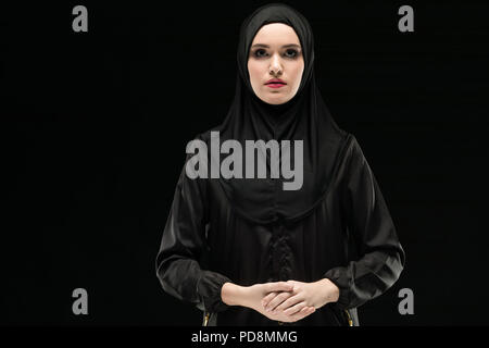 Portrait von schönen jungen zuversichtlich muslimische Frau mit schwarzen Hijab als konservativ Fashion Concept auf schwarzem Hintergrund Stockfoto