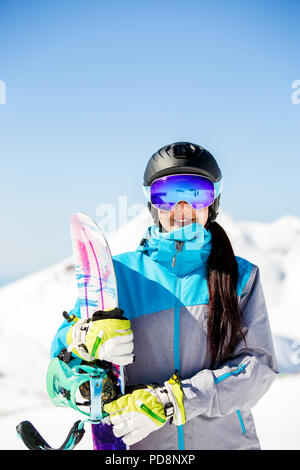Porträt der lächelnde Frau mit Sonnenbrille Sonnenbrille, mit Snowboard auf dem Hintergrund der Schnee in den Bergen Stockfoto