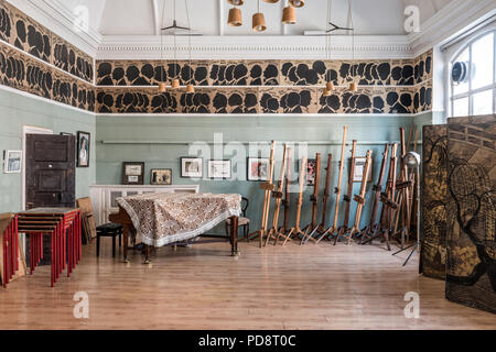 Ein Piano und ein Stapel von staffeleien in den Clubraum des Londoner Sketch Club. Die Silhouetten der letzten Mitglieder zieren die Wand über Stockfoto