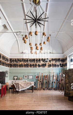 Ein Piano und ein Stapel von staffeleien in den Clubraum des Londoner Sketch Club. Die Silhouetten der letzten Mitglieder zieren die Wand über. Die Leuchte ist Stockfoto