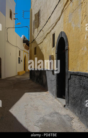 Gasse in ehemaligen portugiesischen Festung. Gelbe Fassade eines Hauses auf der rechten Seite. Traditionelle Tore mit Bögen. Strahlend blauen Himmel. El Jadida, Mo Stockfoto