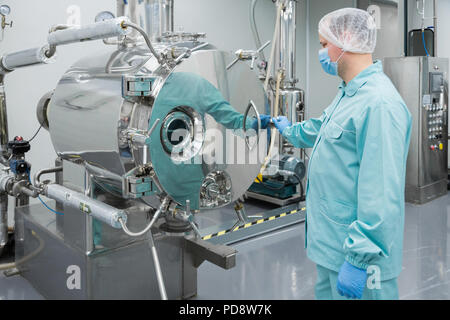 Pharmazeutischen Fabrik mann Arbeiter in Schutzkleidung Arbeiten an Anlagen in sterilen Arbeitsbedingungen Stockfoto