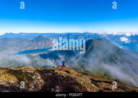 Wanderer mit panorama Blick auf den Lake Atitlan See und Vulkan San Pedro und Toliman früh am Morgen vom Gipfel des Vulkans Atitlan, Guatemala. Wander- und Cl Stockfoto