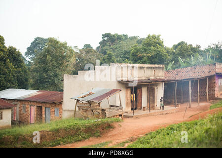 Geschäfte und Häuser säumen den Straßenrand von einer kleinen Stadt im ländlichen Bezirk Mukono, Uganda. Stockfoto