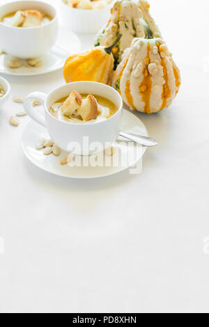 Zwei Schalen mit frischem Kürbis creme Suppe Creme dekoriert, Samen und Cracker auf weiße Tischtuch Stockfoto