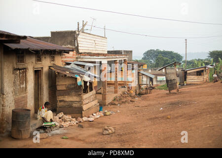 Geschäfte und Häuser säumen den Straßenrand von einer kleinen Stadt im ländlichen Bezirk Mukono, Uganda. Stockfoto