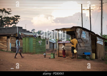 Geschäfte und Häuser säumen den Straßenrand von einer kleinen Stadt im ländlichen Bezirk Mukono, Uganda. Stockfoto