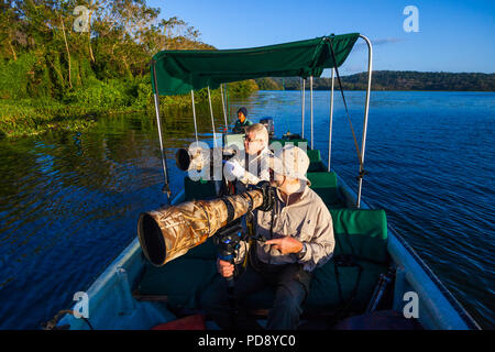 Zwei Naturfotografen mit großen Teleobjektiven in einem Boot auf dem Rio Chagres, Soberania Nationalpark, Republik Panama. Stockfoto