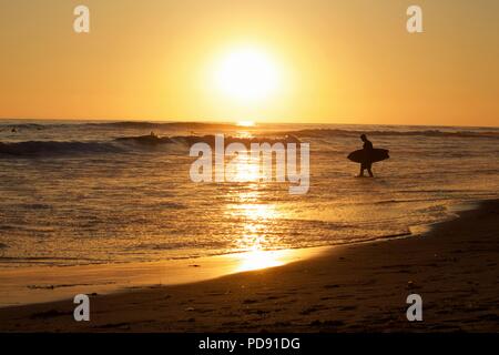 Surfer und Einheimischen nehmen an den Strand und ihre surfbretter während der abschließenden Momente der Tageshelligkeit. Stockfoto