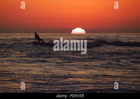 Surfer und Einheimischen nehmen an den Strand und ihre surfbretter während der abschließenden Momente der Tageshelligkeit. Stockfoto