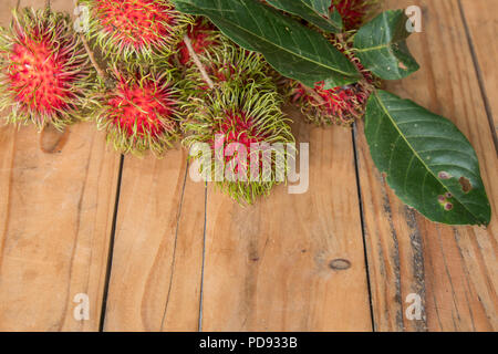 Roten rambutan Nephelium lappaceum auf broun Board. Obst tropischen Baum der Familie Sapindaceae, beheimatet in Südostasien, in vielen Ländern angebaut Stockfoto