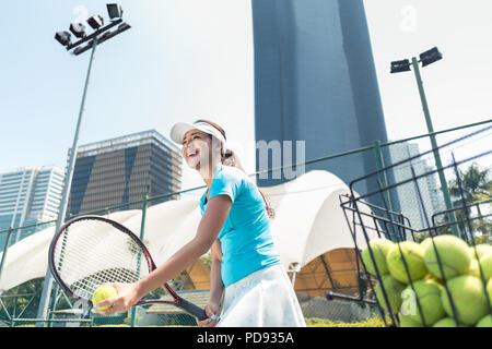 Fröhliche schöne Frau Tennis spielen in einem entwickelten Stadt Stockfoto