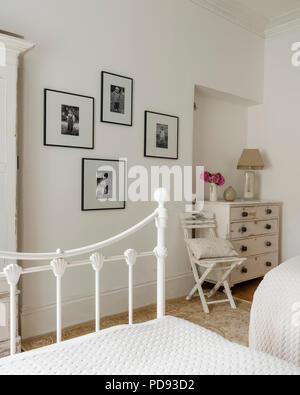 Schwarze und weiße Familie Fotos schmücken die Wand eines Gästeschlafzimmer mit alte Kommode und Patchwork Tagesdecken Stockfoto