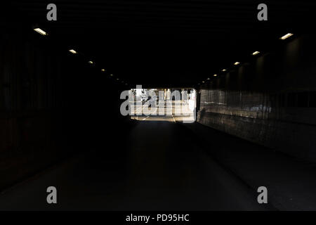 Frauen Silhouette zu Fuß durch U-Bahn Unterführung neben Straße Stockfoto