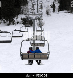 Zwei Skifahrer auf der Sesselbahn in grauer Tag. Kaukasus Berge. Hatsvali, Swaneti Region Georgiens. Quadratisches Bild. Stockfoto