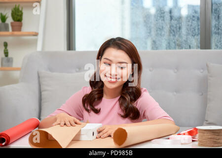 Festliche Hintergrund. Draufsicht auf die Zusammensetzung der Frau Hände wickeln Geschenk für Geburtstag, Muttertag, Valentinstag, März 8. Verpackt Geschenke und Blumen, w Stockfoto