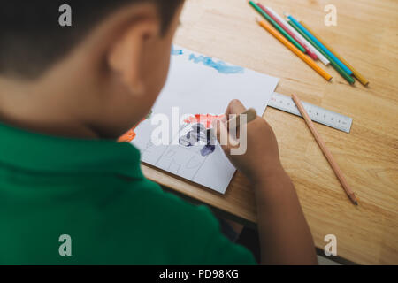 Kleiner Junge zieht am Tisch. Ansicht von oben Stockfoto