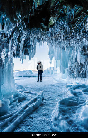 Reisen im Winter, ein Mann stand auf dem zugefrorenen Baikalsee mit Eis Höhle in Irkutsk in Sibirien, Russland Stockfoto