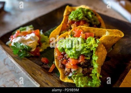 Harte Schale Tacos mit Salat, Koriander, Tomaten, Hackfleisch, und Sauerrahm wie in Indonesien. Stockfoto