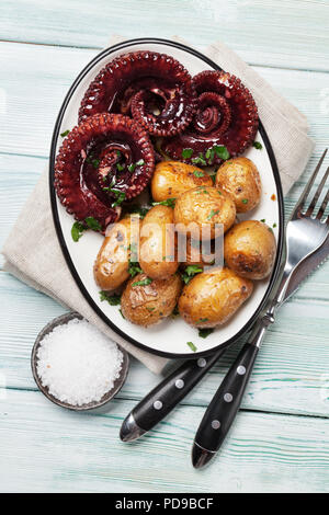 Gegrillter Tintenfisch mit kleinen Kartoffeln mit Kräutern und Gewürzen. Ansicht von oben Stockfoto