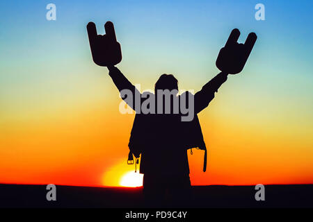 Hände mit Hörner sind in der Lage, bei Sonnenuntergang in eine Lederjacke angehoben Stockfoto