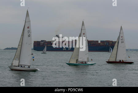 Segelyachten racing während der jährlichen Cowes Week Regatta in den Solent aus der cowes vorbei an einem großen Container Schiff verlässt den Hafen von Southampton Stockfoto