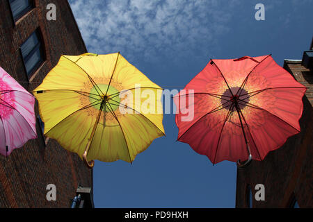 Gelbe und rote Regenschirme hängen über dem Coppergate Shopping Centre, York, North Yorkshire, England, Großbritannien. Stockfoto