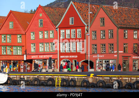 Bergen, Norwegen - 19. November 2017: Gewöhnliche Menschen zu Fuß in der Nähe von traditionellen norwegischen Roten Holzhäuser, Bergen Bryggen Stockfoto